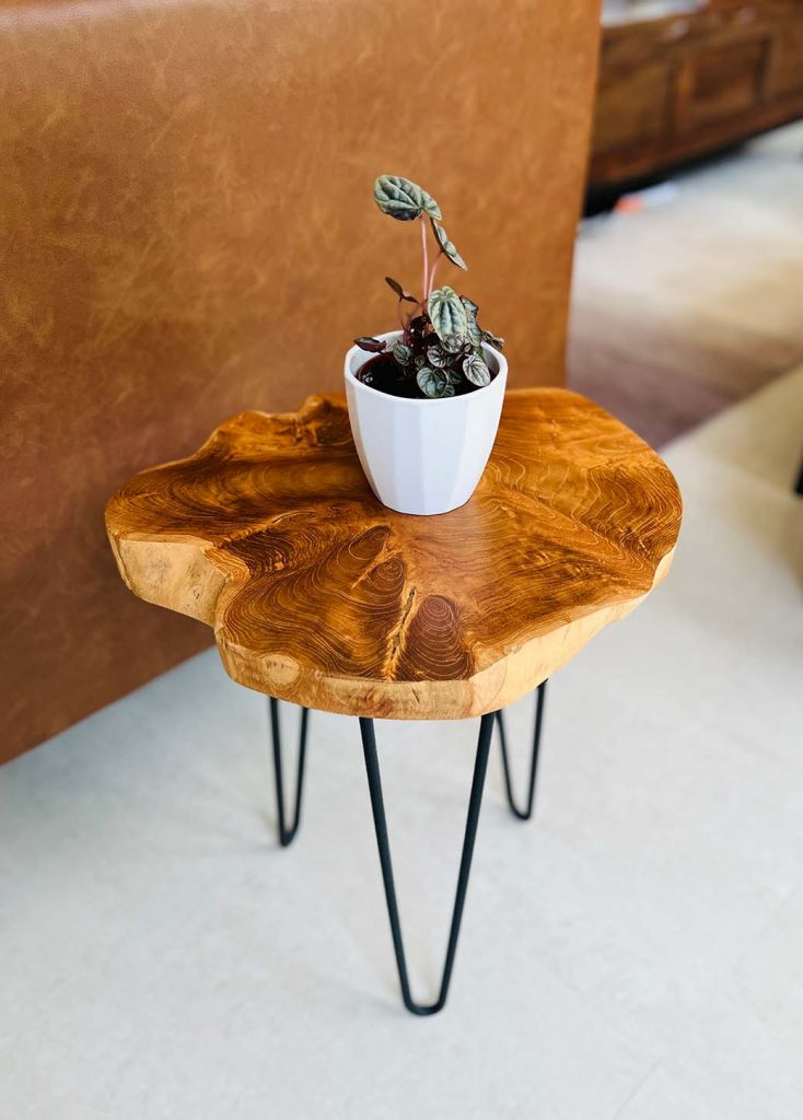 A teak wood side table made using a serving board from Crate and Barrel and mail order tripod legs