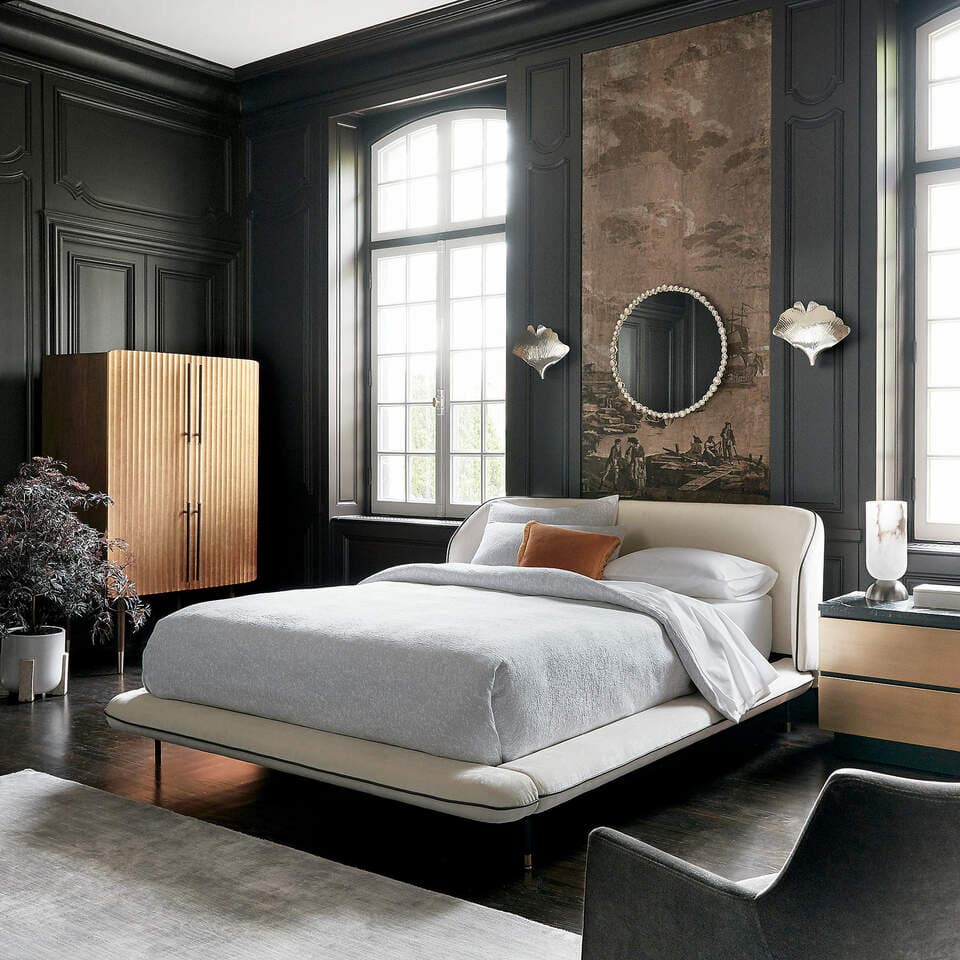 A moody bedroom with a feature panel behind the bed, wood flooring, and a statement cabinet.